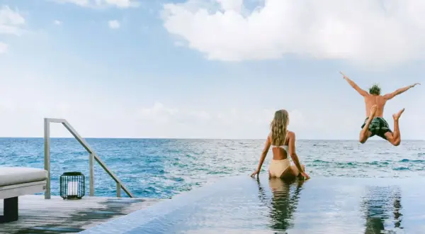 Ein Mann springt ins Meer, während eine Frau zusieht. Perfekte tschechien urlaub tipps für sonnige Tage am Wasser.