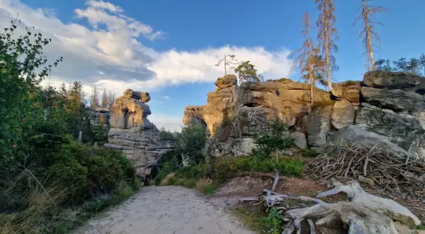 Kamienny labirynt, gdzie skały tworzą naturalne miasto. Ścieżka prowadzi przez skalne miasto, a słońce oświetla majestatyczne formacje.