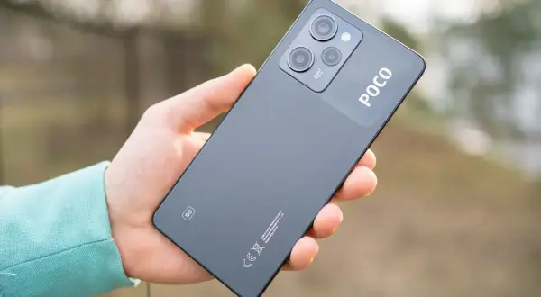 Dłoń trzyma ciemnoszary telefon POCO X5 5G z modułem aparatów i logo POCO.