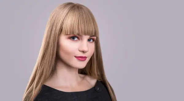 Blondynka z prostą, gęstą grzywką, która zakrywa czoło. Różne rodzaje grzywek mogą podkreślić urodę.