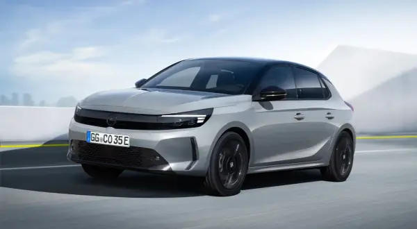 Grå Opel Corsa-e testkörs på en väg med en modern bakgrund.