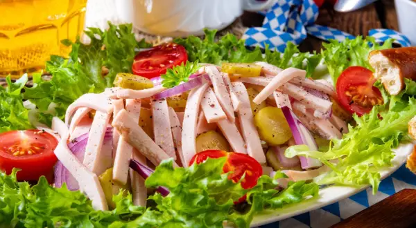 Ein leckerer Wurstsalat mit Tomaten, Gurken und Zwiebeln, perfekt für ein deftiges wurstsalat rezept. Dazu ein Glas Bier.