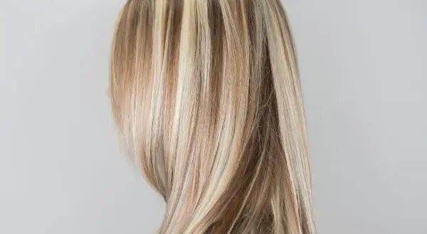 Długie, proste włosy z wyraźnymi refleksami blond, które dodają im głębi i blasku.