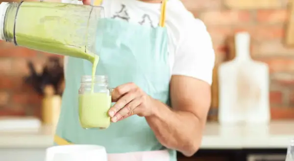 Hombre vertiendo un batido verde cremoso, ideal para quienes buscan alternativas a los tipos de leches vegetales.