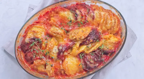 Un gratin patate douce aux tomates et fromage fondant, garni de thym frais, sort tout juste du four.