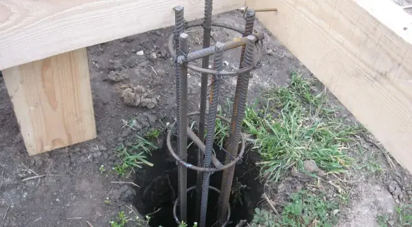 Zbrojenie słupa fundamentowego pod starym drewnianym domem. Przygotowanie do wylania betonu.