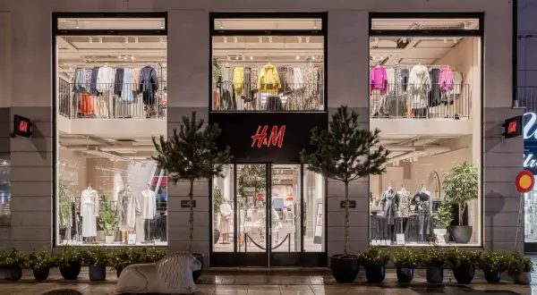 H&M-Filiale bei Nacht. Die Schaufenster zeigen Kleidung, die das Konzept von H&M als Fast Fashion widerspiegelt.
