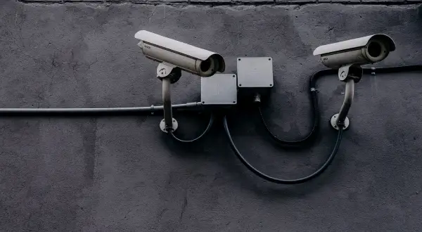 Dwie kamery monitoringu na szarej ścianie. Czy to tylko bezpieczeństwo, czy może coś więcej?