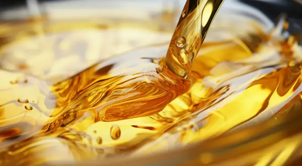Goldener olus oil fließt in eine Schüssel und erzeugt faszinierende Wellen und Blasen.