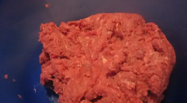 Frisches Hackfleisch, frisch gewolft, bereit für die Zubereitung von Frikadellen. Das gewolft bedeutungsvolle Fleisch liegt in einer blauen Schüssel.
