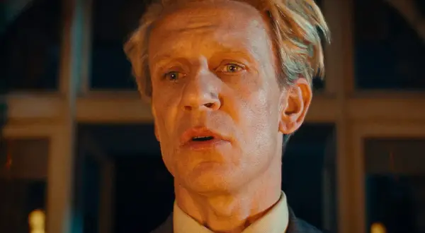 En man med blont hår och en grå kostym, med en blick som säger "och så var de bara en".