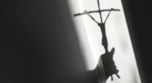 Schatten eines Kreuzes mit Jesusfigur, der eine kritische Auseinandersetzung mit evangelischen Freikirchen andeutet.