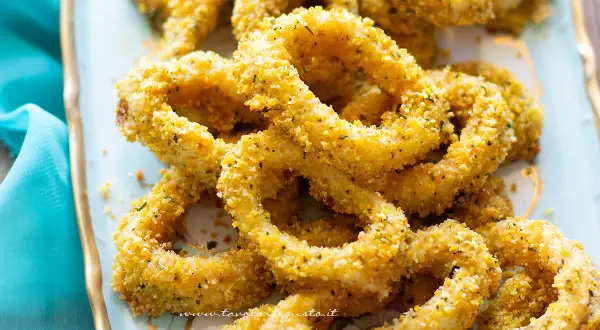 Anelli di totano al forno, dorati e croccanti, serviti su un piatto azzurro con un tovagliolo turchese.