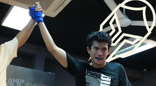 A boxer's corner man raises his hand in victory, celebrating a hard-fought win.