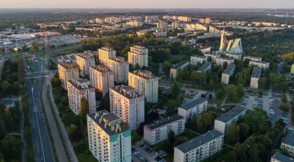 Widok z lotu ptaka na osiedle bloków mieszkalnych i drogę z samochodami o zachodzie słońca.
