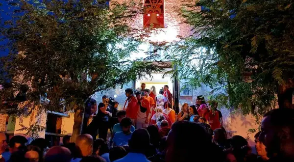 Multitud reunida frente a una iglesia iluminada, disfrutando de las fiestas de Calatayud.