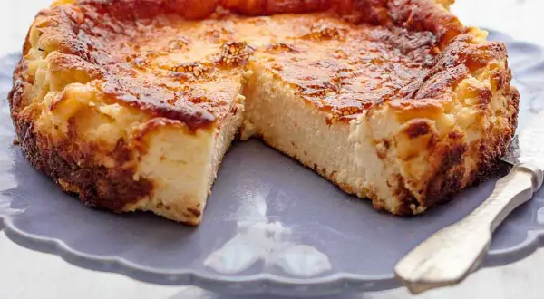 Tarta de queso de la Viña, dorada y cremosa, servida en un plato morado.