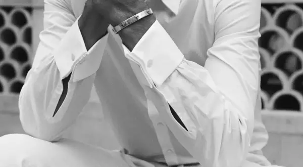 Un homme porte une chemise manchette homme blanche, ornée d'un bracelet argenté.