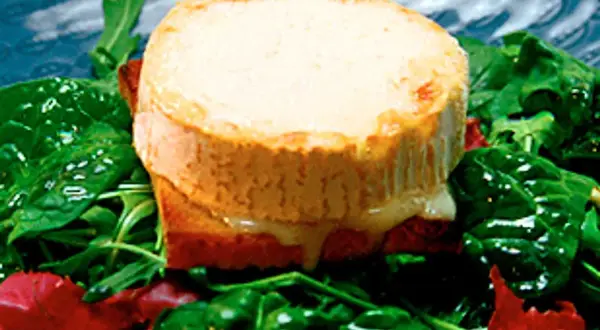Varm chevre chaud på rostat bröd, serverad med en fräsch sallad av spenat och ruccola. Smältande ost och gröna blad.