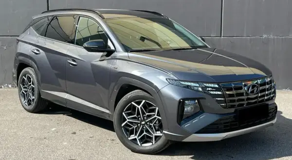 Szary Hyundai Tucson, jeden z najnowszych hyundai suv modele, z charakterystycznymi felgami i nowoczesnym designem, zaparkowany na tle szarej ściany.