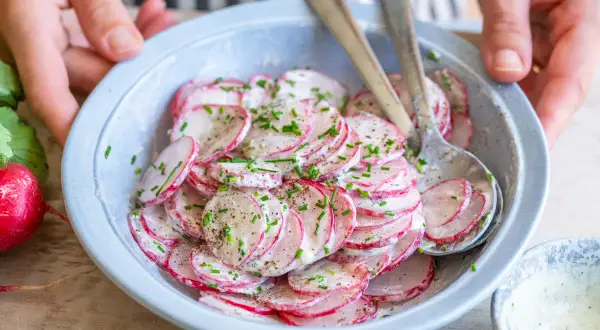 Frischer Radieschen Salat mit Schnittlauch und einer cremigen Soße, bereit zum Servieren.