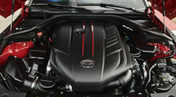 El potente motor del Supra, con su distintivo logo de Toyota y detalles rojos, listo para la acción.