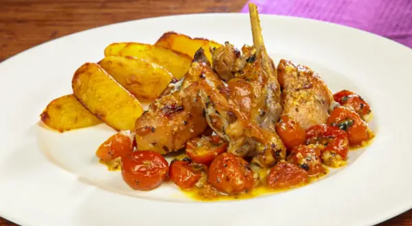 Piatto di coniglio al forno con patate arrosto e pomodorini confit.