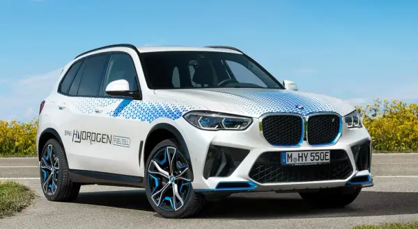 Białe BMW X5 z niebieskimi akcentami i napisem "BMW HYDROGEN FUEL CELL" na drzwiach, symbolizujące przyszłość motoryzacji.