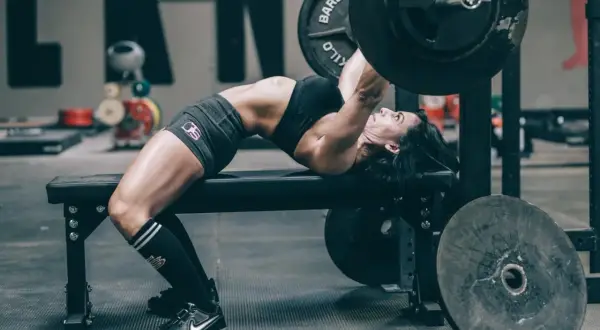 Frau hebt mit starkem Rücken und angespannten Muskeln eine Hantel im Rahmen des German Volume Training.