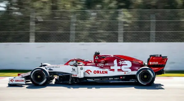 Biało-czerwony bolid Alfa Romeo F1 z numerem 7 pędzi po torze.