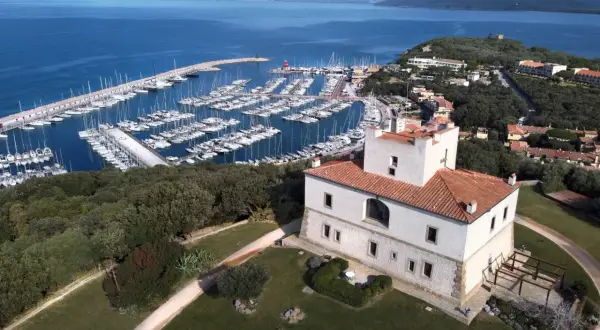 Punta Ala: un castello bianco con tetto rosso domina un porto turistico pieno di barche e il mare blu. Cosa vedere in questo luogo incantevole.