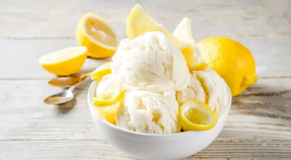 Schüssel mit cremigem Zitroneneis, garniert mit frischen Zitronenscheiben. Perfekt, um Zitroneneis selber machen zu genießen.