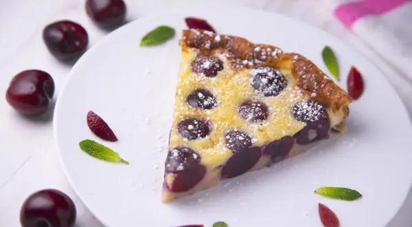Une part de clafoutis aux cerises, saupoudrée de sucre glace, comme le ferait Cyril Lignac.