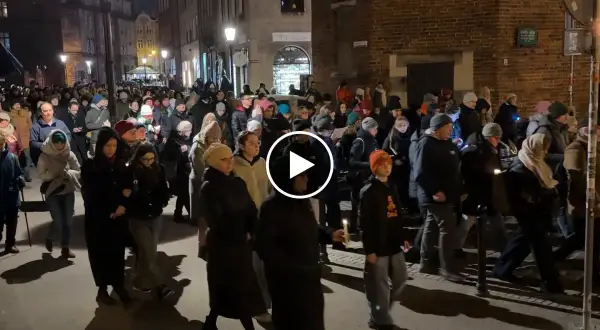 Tłum ludzi idzie ulicą nocą, trzymając świece. To uroczysta chwila, kiedy jest droga krzyżowa.