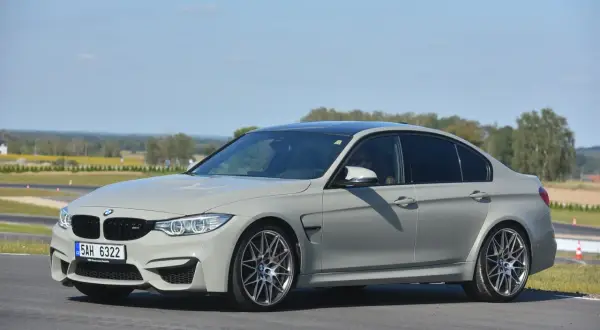 Szare BMW M3 F80 na torze wyścigowym, z widocznym kierowcą.