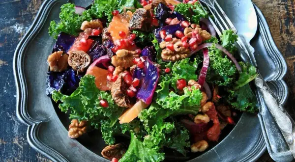 En färgglad sallad med grönkål, granatäpple, apelsin och valnötter, perfekt som en frisk sallad till julbordet.