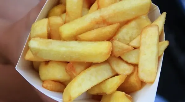 Złociste, grube frytki belgijskie w papierowym rożku.