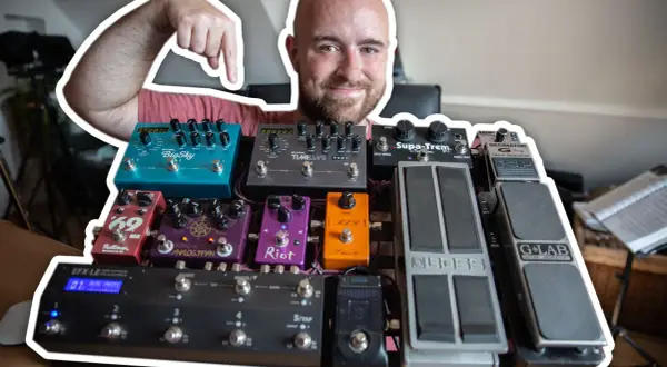 Uśmiechnięty mężczyzna pokazuje swoją bogatą kolekcję efektów gitarowych, prezentując ich kolejność na pedalboardzie.