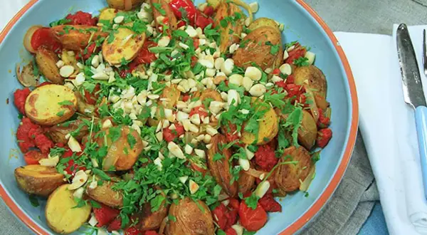 En härlig varm potatissallad med rostade potatisar, tomater och nötter, toppad med färsk persilja. Perfekt som tillbehör.
