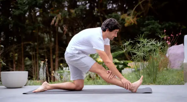 Un homme s'étire sur un tapis, se demandant combien de temps durent les courbatures après son entraînement.