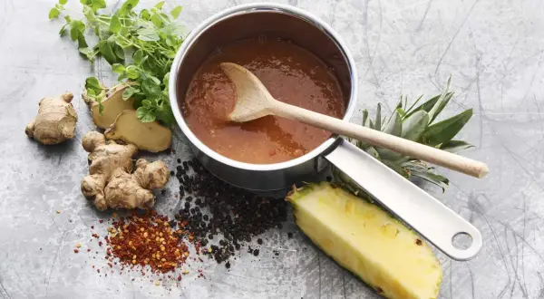 En kastrull med sötsur sås som på kinarestaurang, med ingefära, ananas, pepparkorn och chiliflakes.