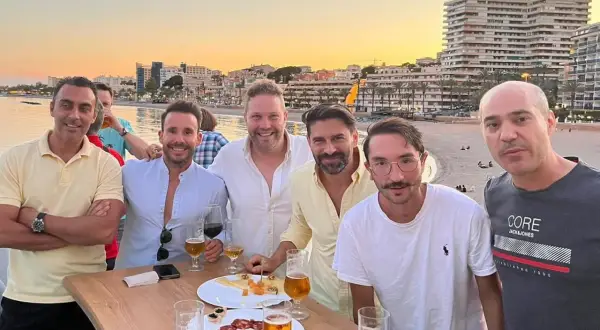 Amigos brindan en el puerto de Aguadulce de noche, con el mar y edificios de fondo.