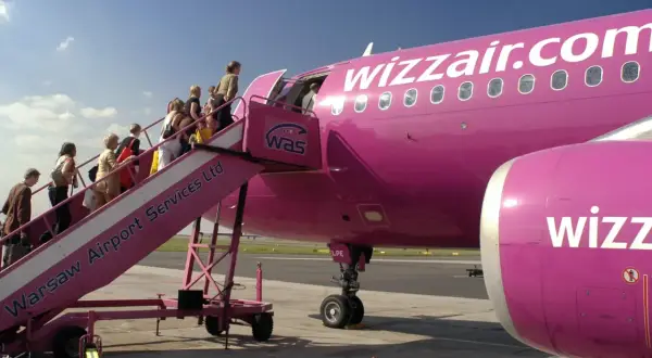 Pasażerowie wsiadają do różowego samolotu Wizzair. Kiedy odprawa online? Już teraz!