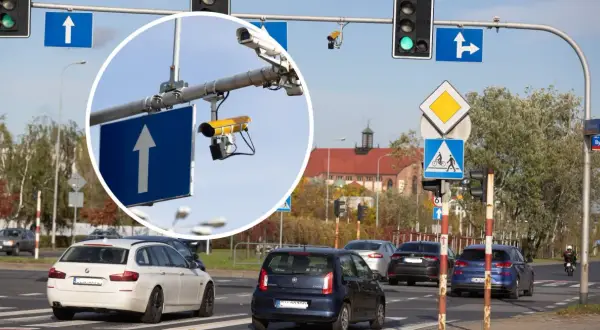 Kamery na skrzyżowaniach rejestrują wykroczenia. Widok na ruchliwe skrzyżowanie z sygnalizacją świetlną i znakami drogowymi.