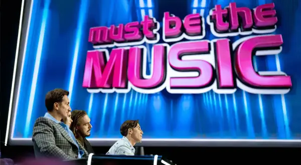 Trzech jurorów siedzi przed ekranem z napisem "must be the MUSIC".