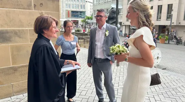 Hochzeitsmesse Heilbronn: Ein Paar feiert seine Hochzeit mit einem Blumenstrauß vor einer Kirche.