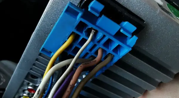 Niebieska wtyczka z przewodami, w tym żółtym i białym, podłączona do radia samochodowego. Prawdopodobnie część instalacji CAN bus.