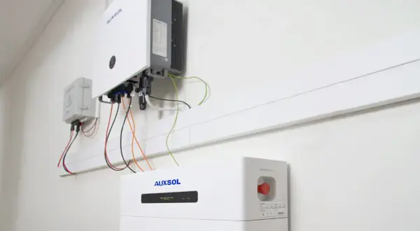 Nowoczesny bank energii do domu, zamontowany na ścianie, z widocznym falownikiem i modułem bateryjnym.