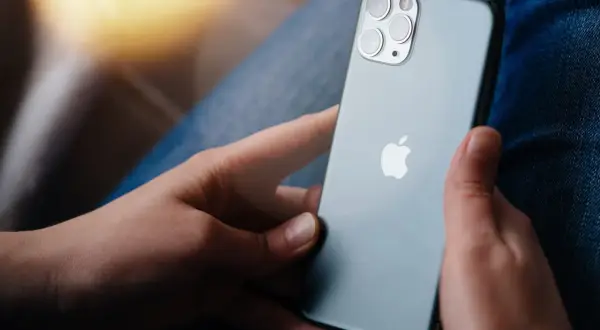 Osoba trzyma iPhone'a, zastanawiając się, jak zresetować iPhone do ustawień fabrycznych bez hasła.