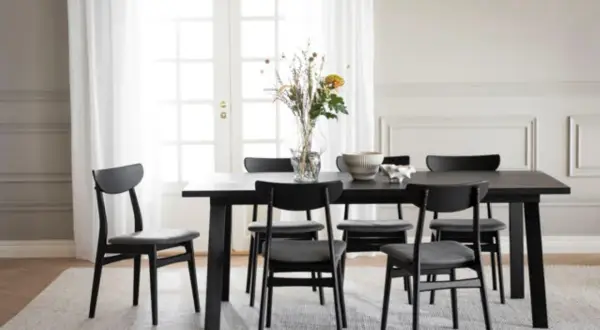 Ett modernt matbord med sex svarta stolar. Utrymme runt matbordet är inrett med en vas med blommor och en skål.